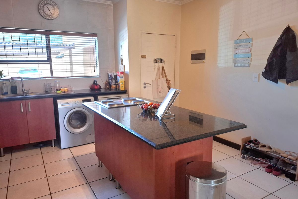 A functional kitchen featuring a central island with a built-in hob, granite countertops, tiled flooring, and ample under-counter storage space.