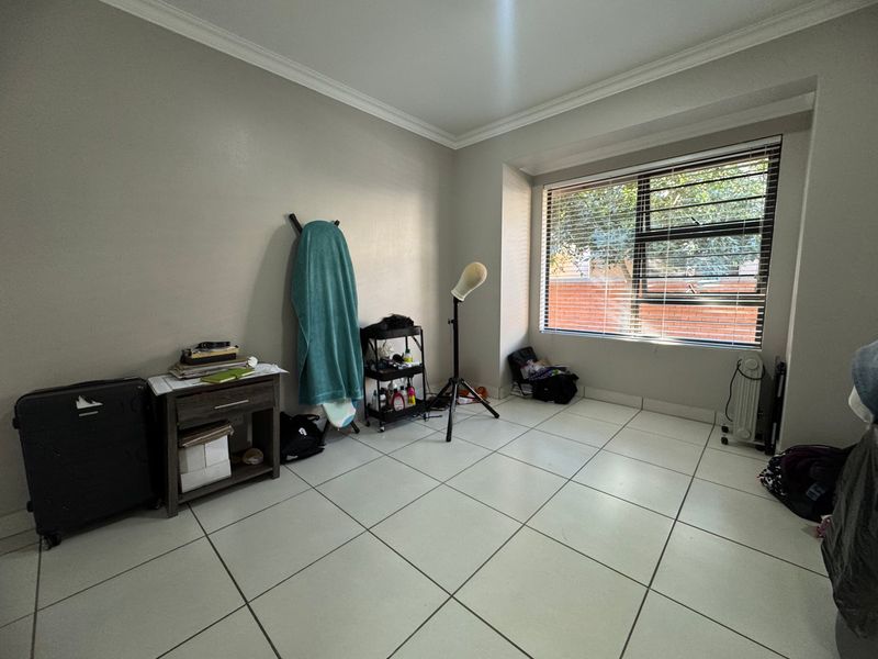 A bedroom featuring tiled flooring, coved cornicing, and a window fitted with security bars and venetian blinds.