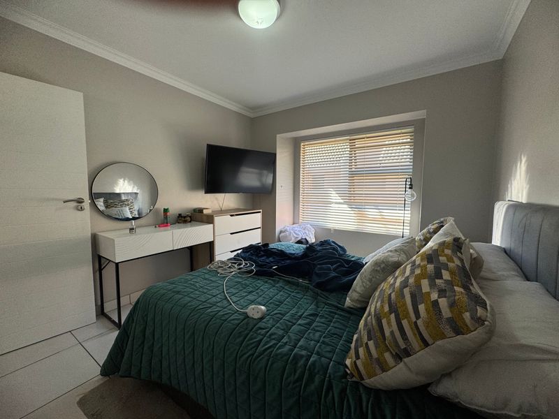 A well-maintained bedroom featuring tiled flooring, neutral wall tones, and a window fitted with horizontal blinds, providing a comfortable and functional living space.