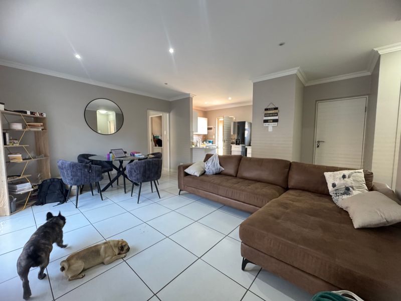 Spacious open-plan living and dining area featuring neutral wall tones, tiled flooring, and recessed lighting, with a seamless flow into the adjacent kitchen space.