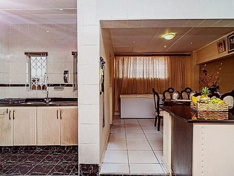 Open plan kitchen and dining area featuring tiled flooring, built-in cabinetry, and a tiled splashback, offering a functional layout for daily living.