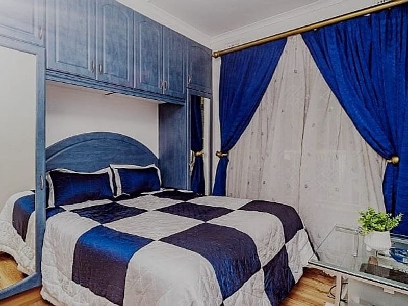 A bedroom featuring extensive built-in blue cabinetry with integrated mirrored wardrobe doors and laminate flooring.