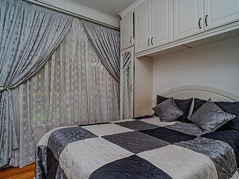 A bedroom featuring built-in cabinetry with integrated mirrored doors, hardwood flooring, and coved ceiling details.