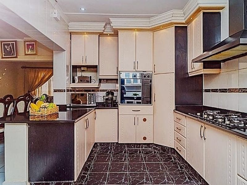 A functional kitchen featuring built-in cabinetry, granite countertops, a gas hob with extractor fan, and a built-in oven, finished with tiled flooring and backsplash.