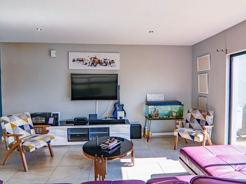 A bright living room featuring neutral wall tones, large format floor tiles, and a sliding glass door providing access to the outdoor area.