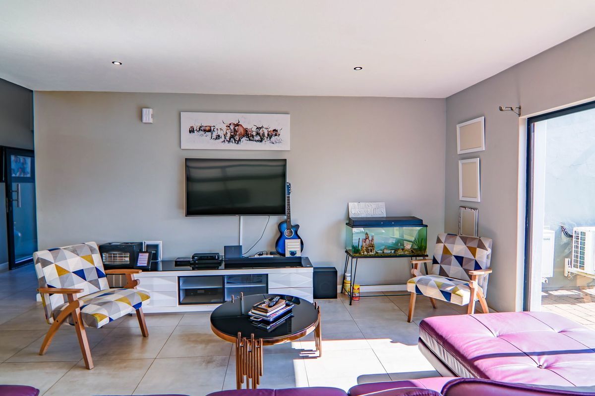 A bright living room featuring neutral wall tones, large format floor tiles, and a sliding glass door providing access to the outdoor area.