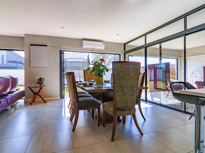 Spacious open-plan living and dining area featuring large aluminium-framed sliding glass doors that provide seamless access to the outdoor space.