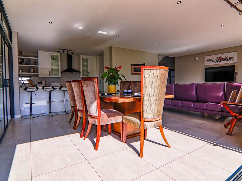 Spacious open-plan living and dining area featuring modern tiled floors, recessed lighting, and a sleek kitchen with integrated cabinetry and breakfast bar.