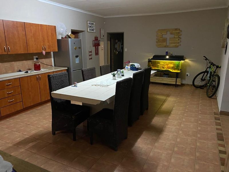 Open plan kitchen and dining area featuring wooden cabinetry and tiled flooring, providing a functional space for family meals and food preparation.