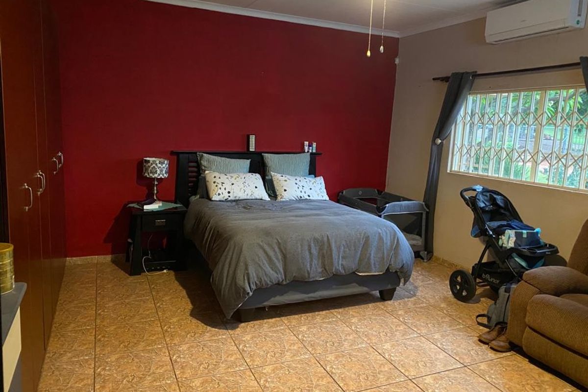 Spacious bedroom featuring tiled flooring, built-in cupboards, and a wall-mounted air conditioning unit, providing a functional and comfortable living space.