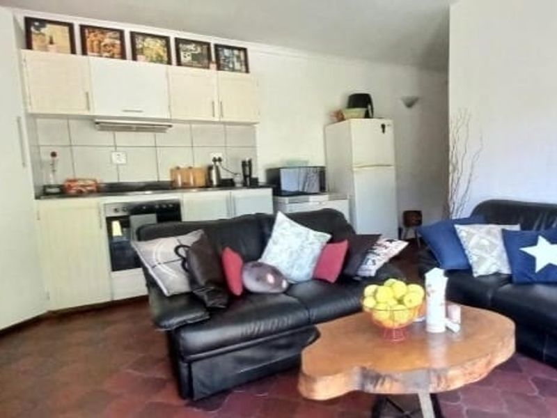 Open-plan living area featuring a functional kitchen with built-in cabinetry, oven, and extractor fan, seamlessly connected to the lounge space.