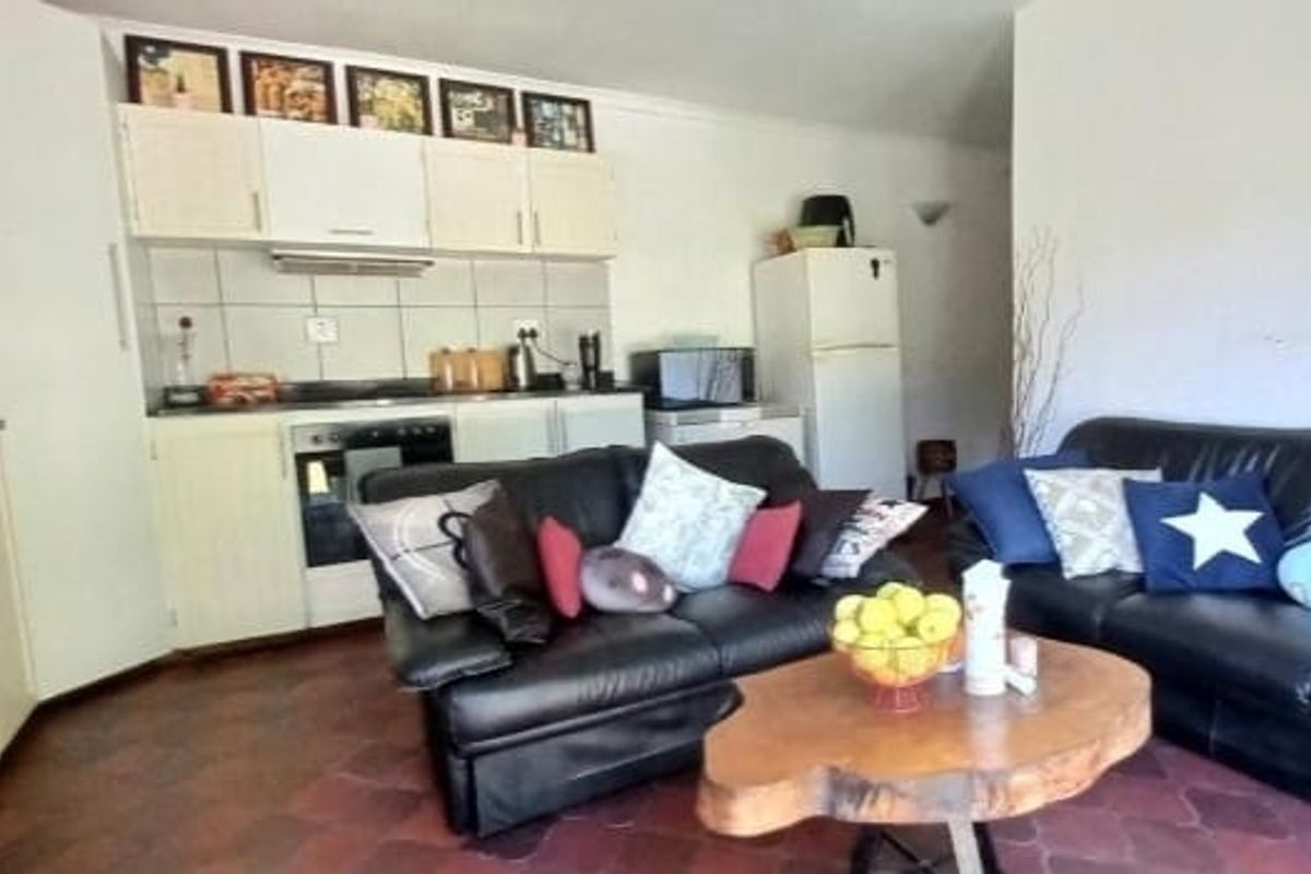 Open-plan living area featuring a functional kitchen with built-in cabinetry, oven, and extractor fan, seamlessly connected to the lounge space.