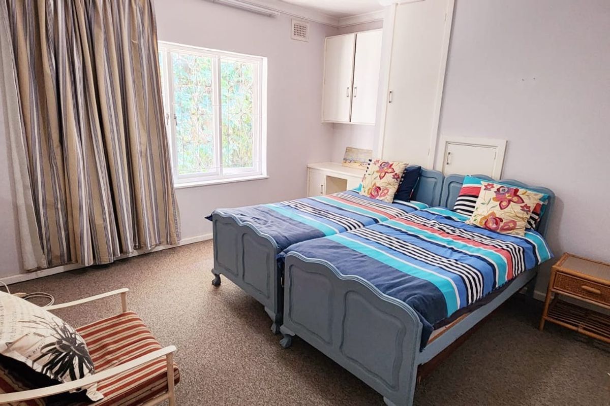 A functional bedroom featuring built-in cabinetry, a built-in wardrobe, and carpet flooring, offering a practical layout for a sleeping space.