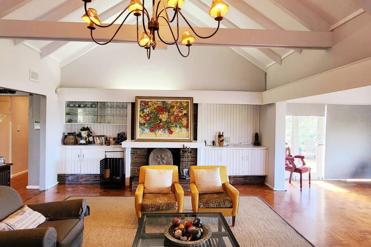 Spacious living room featuring a vaulted ceiling with exposed beams, a central fireplace with built-in cabinetry, and warm parquet flooring.