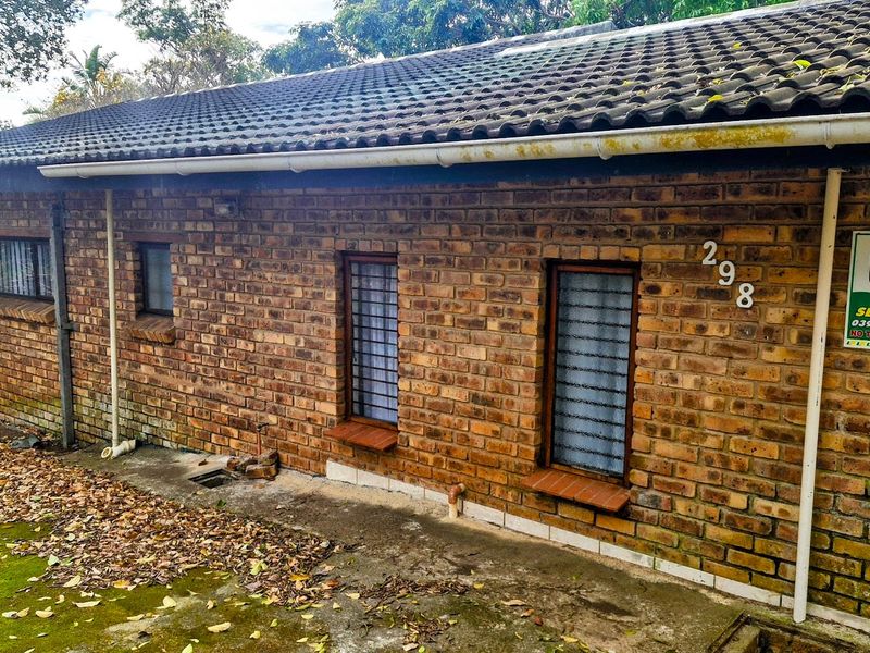 Rear exterior view of a face brick house featuring tiled roofing, security bars on windows, and established guttering.