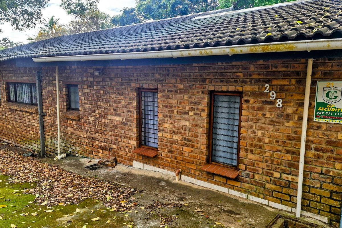 Rear exterior view of a face brick house featuring tiled roofing, security bars on windows, and established guttering.