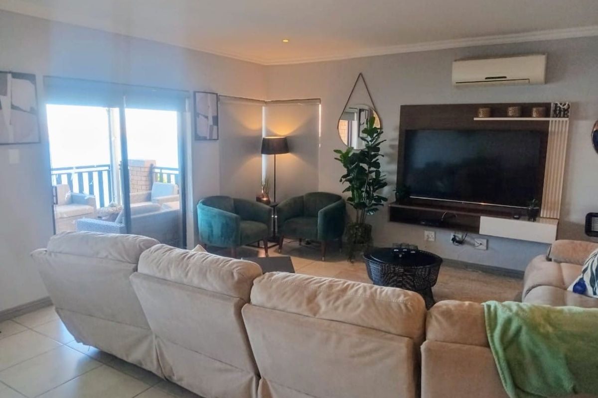 A comfortable living room featuring a built-in media unit, split-system air conditioning, and sliding glass doors leading to an outdoor patio area.