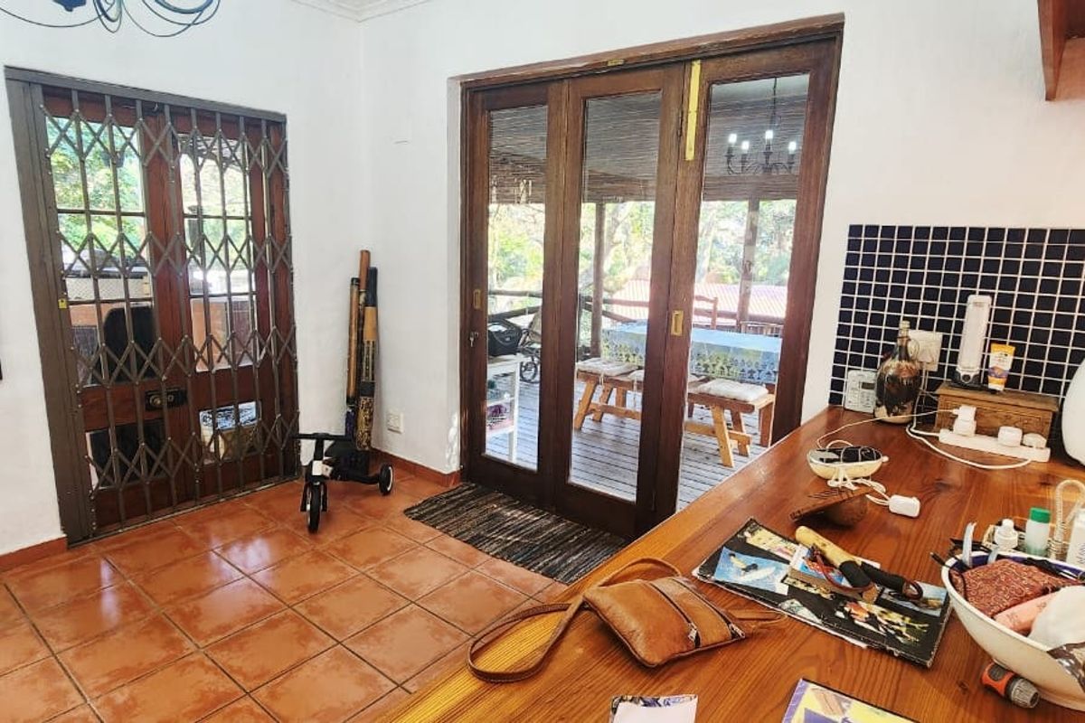 Kitchen area featuring a wooden countertop, black tiled splashback, and timber-framed glass doors leading to an outdoor patio space.