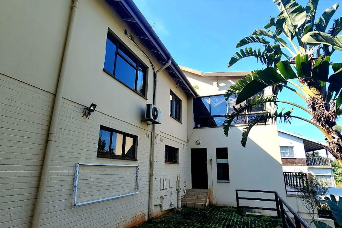Rear elevation of the house featuring aluminium windows, an air conditioning unit, and a paved outdoor area with a wall-mounted clothesline.