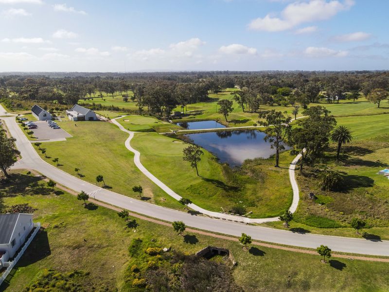 An aerial view of a residential estate featuring a golf course, water features, and well-maintained paved pathways and road infrastructure.