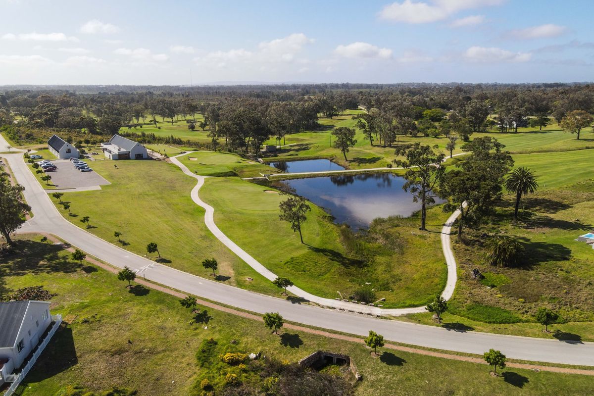 An aerial view of a residential estate featuring a golf course, water features, and well-maintained paved pathways and road infrastructure.