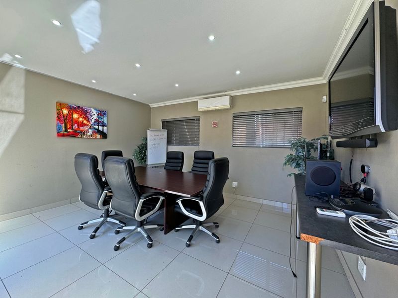 A functional office space featuring tiled flooring, recessed downlighting, and a wall-mounted air conditioning unit.