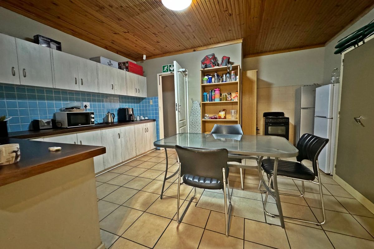 A functional kitchen featuring built-in cabinetry, a tiled backsplash, and a timber ceiling, offering a practical layout with space for a dining area.