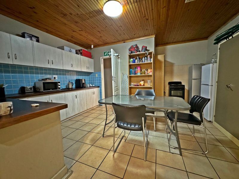 A functional kitchen featuring built-in cabinetry, a tiled backsplash, and a timber ceiling, offering a practical layout with space for a dining area.