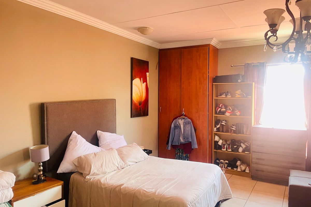 A functional bedroom featuring tiled flooring, a built-in wardrobe, and decorative ceiling cornicing, offering a comfortable and practical living space.