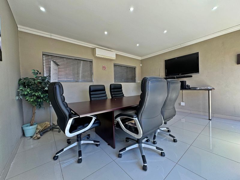 A functional office space featuring tiled flooring, recessed lighting, and a wall-mounted air conditioning unit.