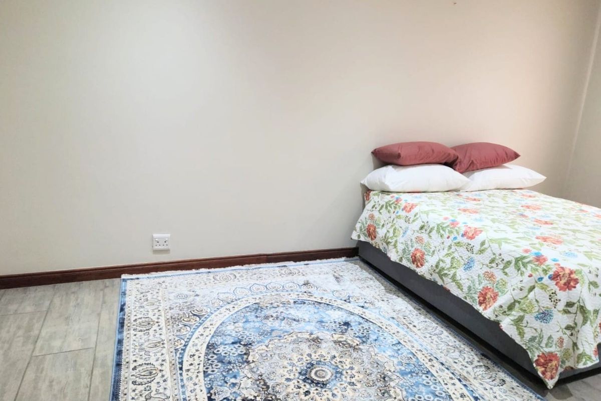 A simple bedroom featuring neutral walls, tiled flooring, and dark wood-tone skirting boards.