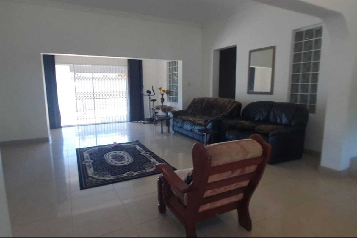 Spacious living area featuring tiled flooring, an arched entryway, and a glass block window, providing a bright and open layout.