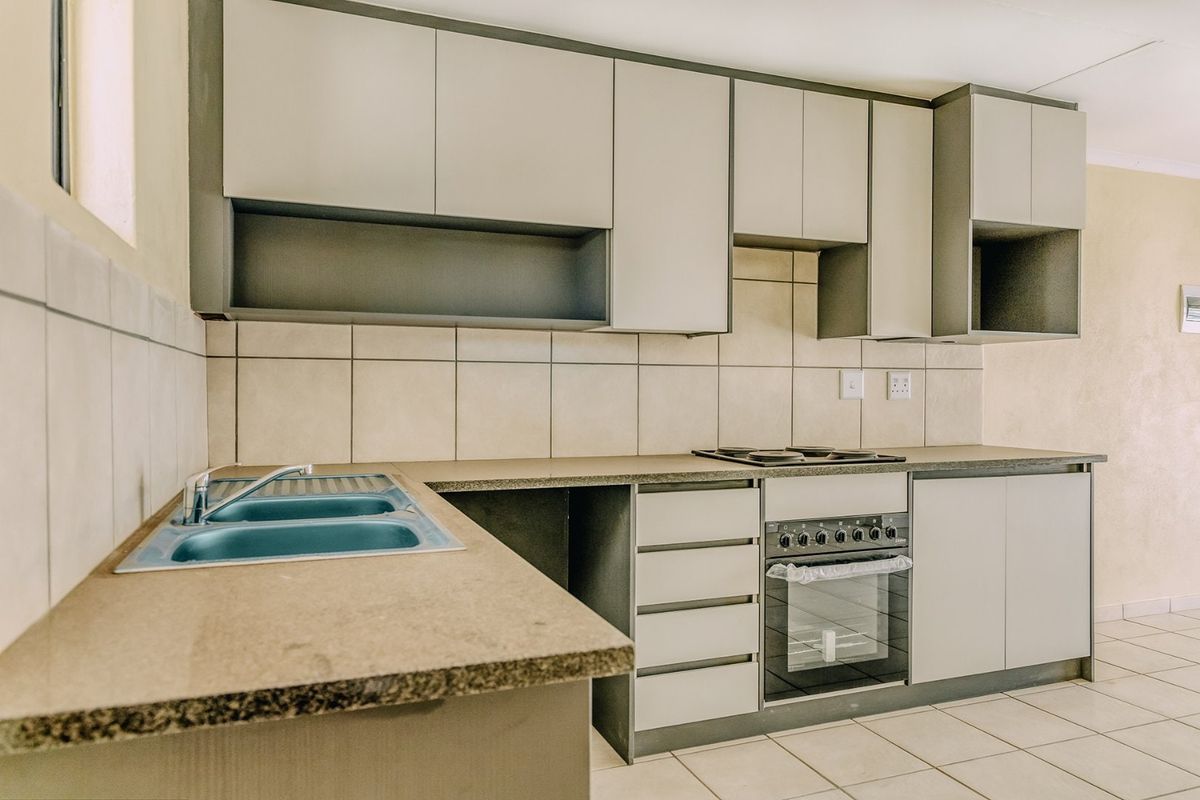 A functional kitchen featuring built-in cabinetry, laminate countertops, a stainless steel sink, and a built-in oven with an electric hob.