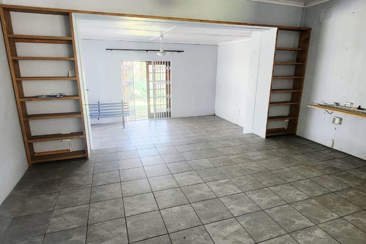 An empty living area featuring ceramic floor tiles, built-in wooden shelving units, and a sliding door leading to the exterior.