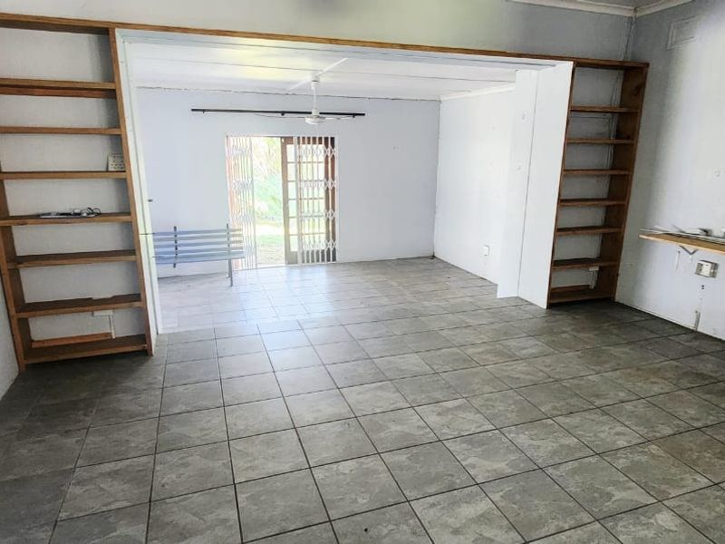 An empty living area featuring ceramic floor tiles, built-in wooden shelving units, and a sliding door leading to the exterior.