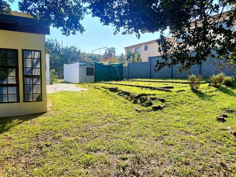 Rear garden area featuring a terraced lawn, boundary wall, and a small outbuilding, offering potential for landscaping and outdoor improvement.