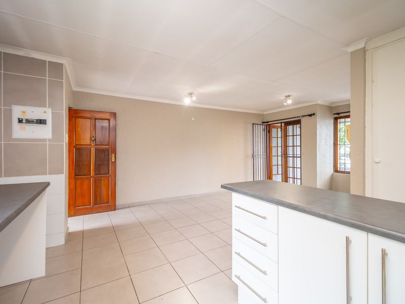 Spacious open-plan living and kitchen area featuring tiled flooring, neutral walls, and direct access to an outdoor patio through a sliding door.