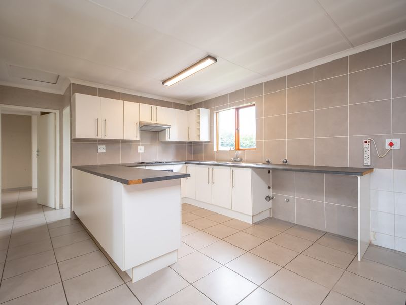 A functional, empty kitchen featuring white cabinetry, tiled splashbacks, laminate countertops, and tiled flooring, ready for personalization or modern updates.