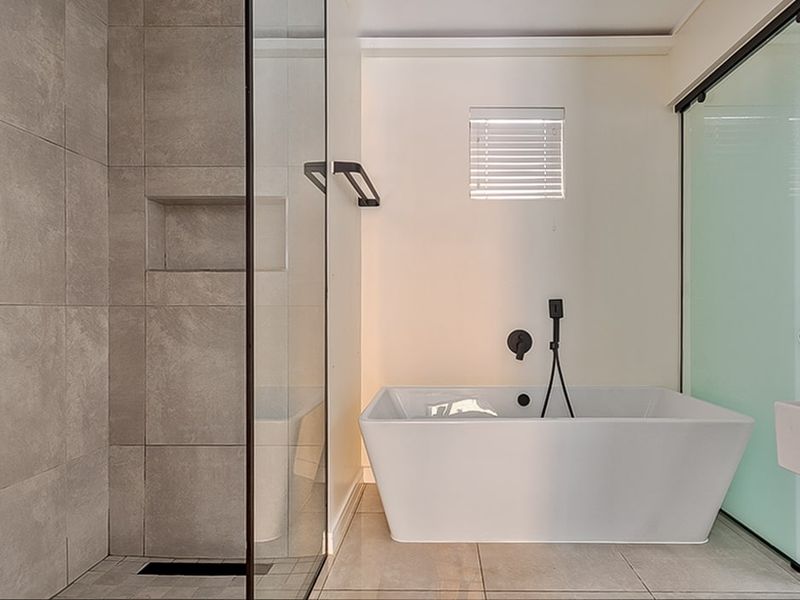 Modern bathroom featuring a sleek freestanding bathtub, a spacious walk-in shower with a built-in niche, and contemporary black matte fixtures.