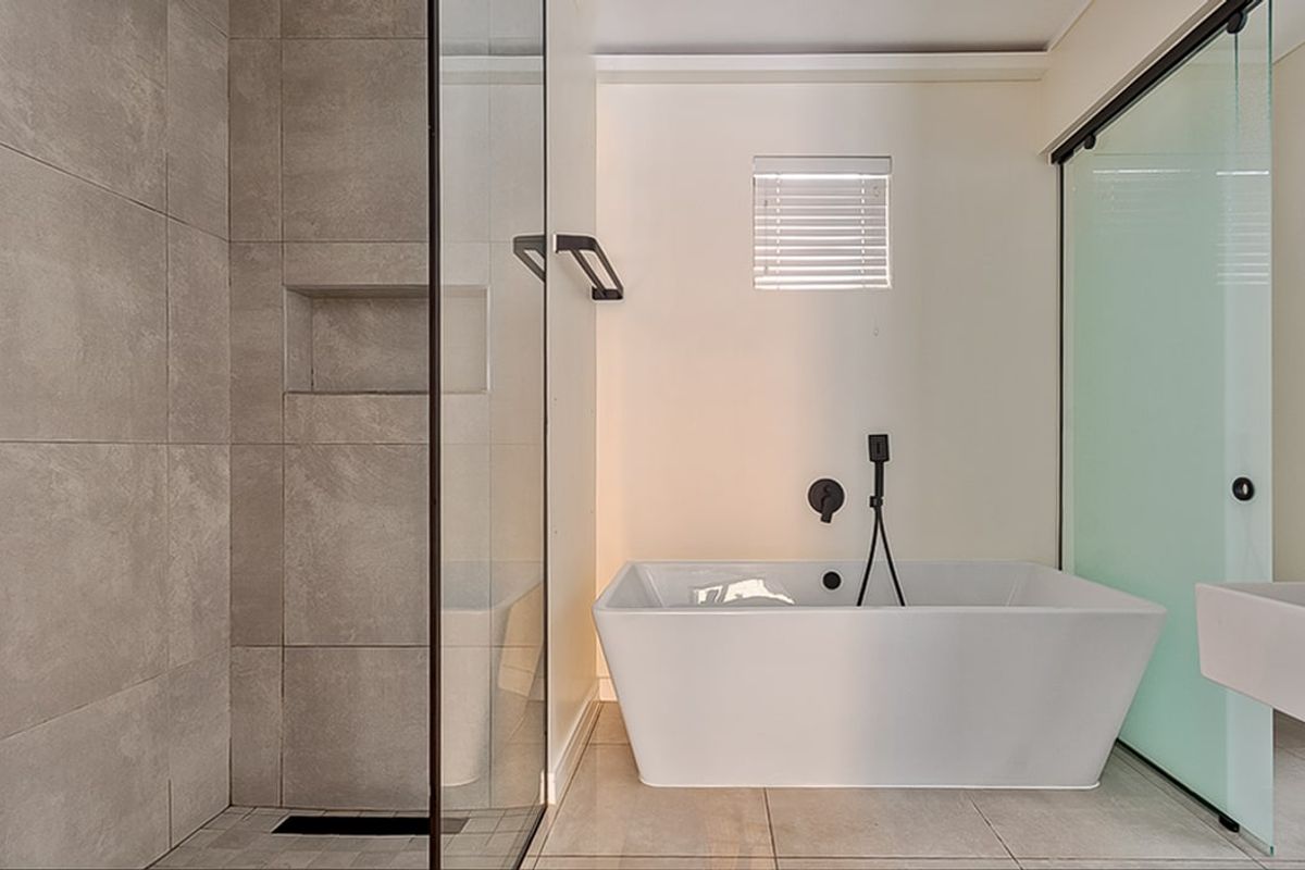 Modern bathroom featuring a sleek freestanding bathtub, a spacious walk-in shower with a built-in niche, and contemporary black matte fixtures.