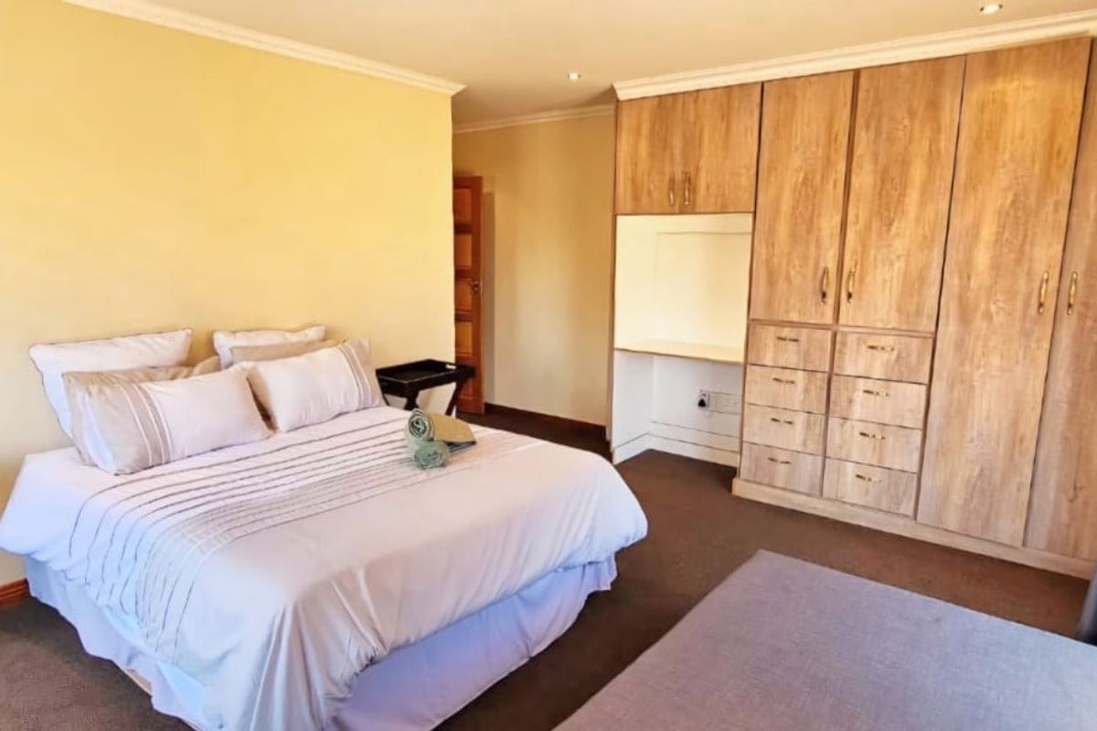A well-maintained bedroom featuring extensive built-in wooden cabinetry, a integrated desk area, and neutral carpeting.