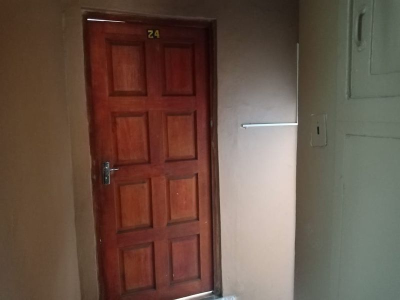 A simple interior hallway featuring a wooden panel door and basic wall finishes.