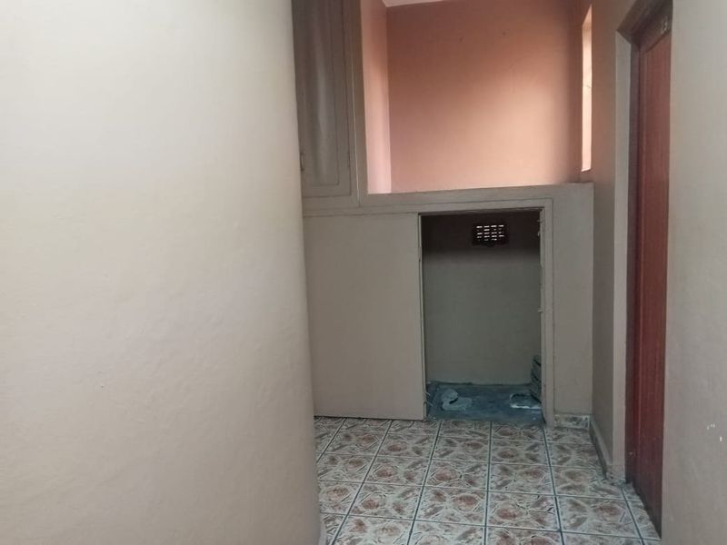 A small, empty utility or storage space featuring built-in cabinetry and tiled flooring, requiring cosmetic updates to improve its overall condition.