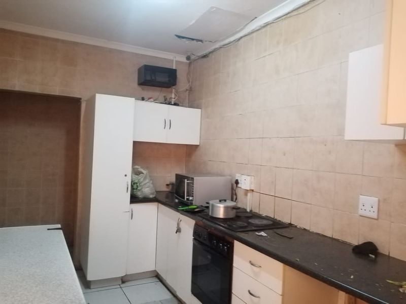 A dated kitchen featuring built-in cabinetry, an electric hob, and oven, currently requiring maintenance and cosmetic updates to the ceiling and finishes.