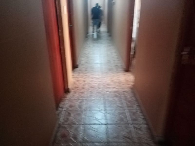 A narrow residential hallway featuring tiled flooring and multiple internal door access points.