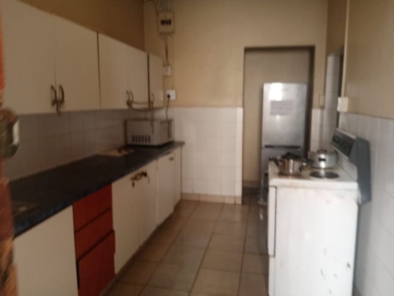A functional kitchen featuring built-in cabinetry, tiled splashbacks, and tiled flooring, offering a dated layout ready for modernization.