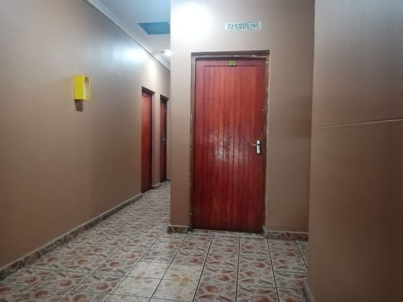 A functional interior hallway featuring tiled flooring and multiple wooden doors providing access to various rooms.