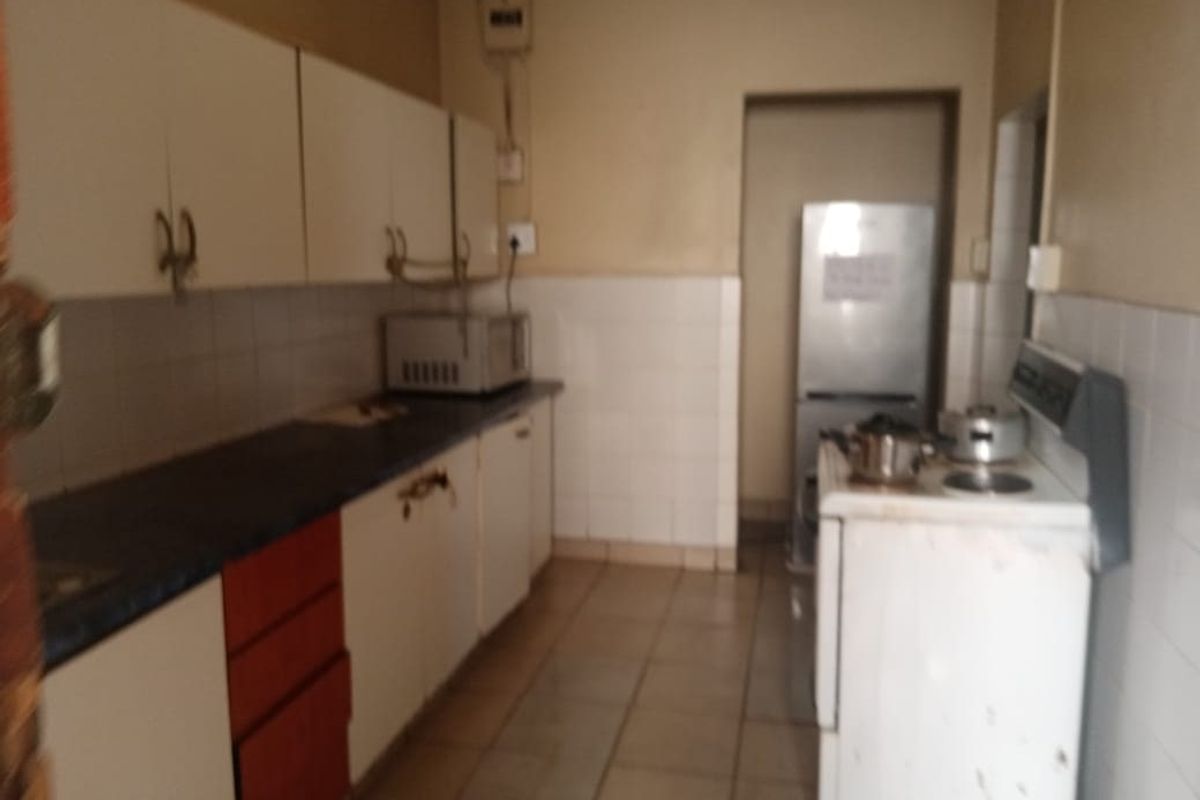 A functional kitchen featuring built-in cabinetry, tiled splashbacks, and tiled flooring, offering a dated layout ready for modernization.