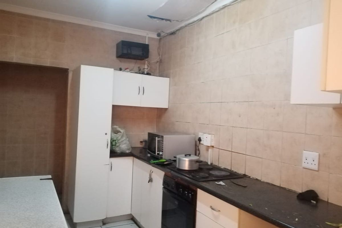 A dated kitchen featuring built-in cabinetry, an electric hob, and oven, currently requiring maintenance and cosmetic updates to the ceiling and finishes.