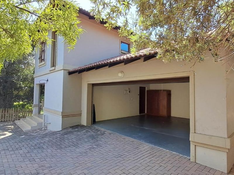 A view of the exterior front of the property featuring a paved driveway and a spacious open garage area.